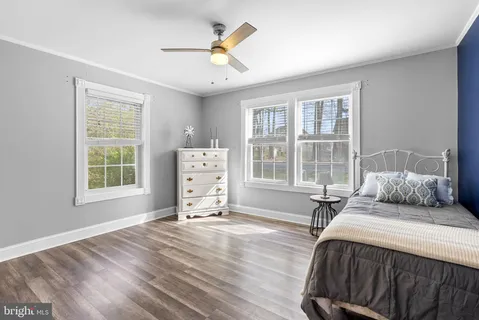 a spacious bedroom with a bed a dresser and windows