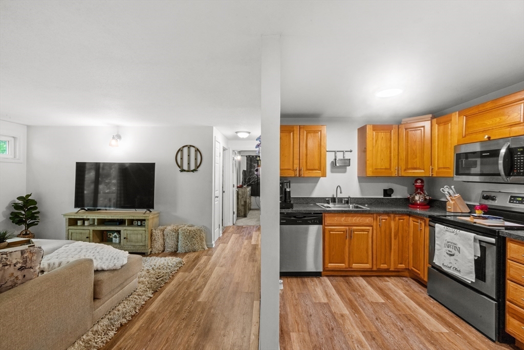 1619 Braley Road, Unit 97 New Bedford, MA 02745 - Photo 8 of 27 a large kitchen with stainless steel appliances granite countertop a stove top oven a sink dishwasher a dining table and chairs with wooden floor