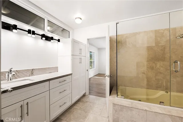 a bathroom with a granite countertop sink a mirror a bathtub and shower