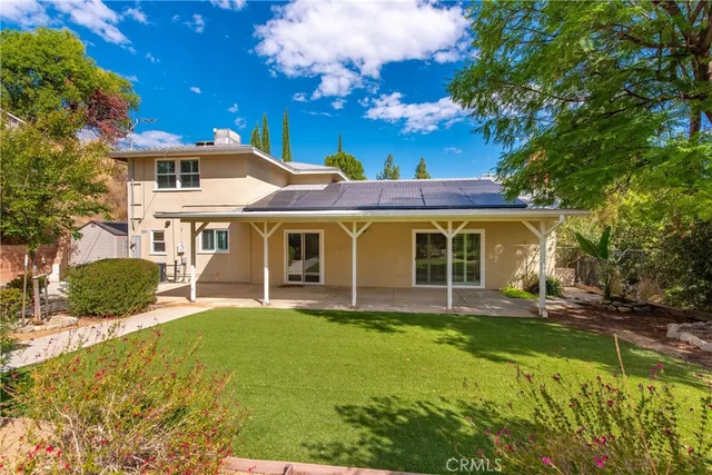 a view of a house with a big yard and large tree