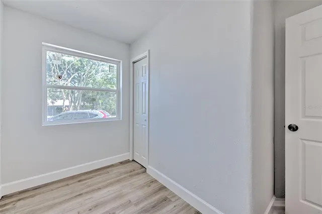 a view of an empty room with wooden floor and a window
