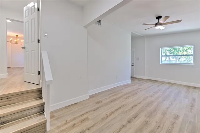 a view of empty room with wooden floor and fan
