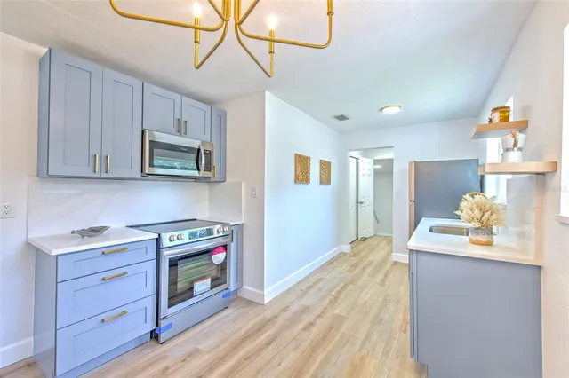 a kitchen with stainless steel appliances granite countertop a stove a sink dishwasher and a microwave with wooden floor