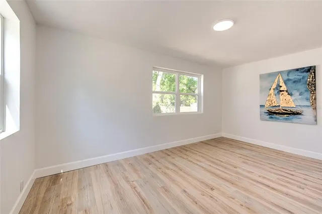 an empty room with wooden floor cabinet and windows