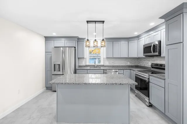 a large kitchen with granite countertop a stove and a sink