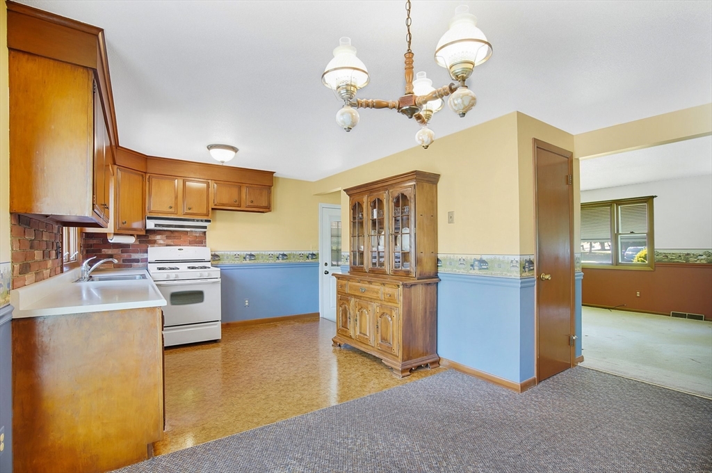 100 Penncastle Street Springfield, MA 01129 - Photo 11 of 26 a kitchen with stainless steel appliances granite countertop a refrigerator a stove oven a sink dishwasher a dining table and chairs with wooden floor