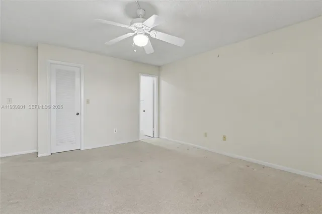 an empty room with a ceiling fan and a window