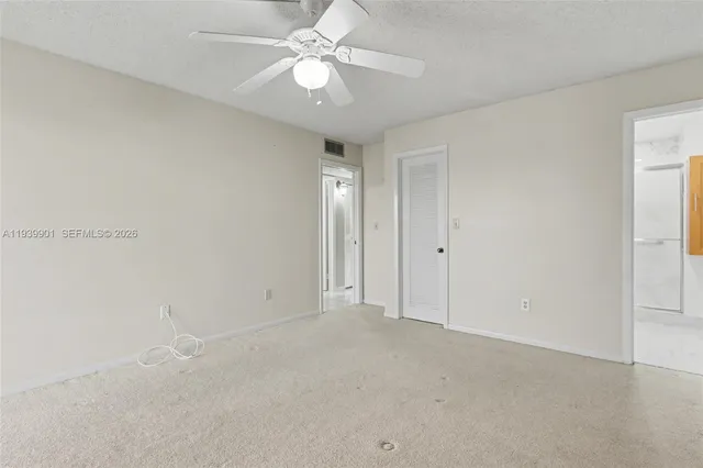 an empty room with windows and ceiling fan