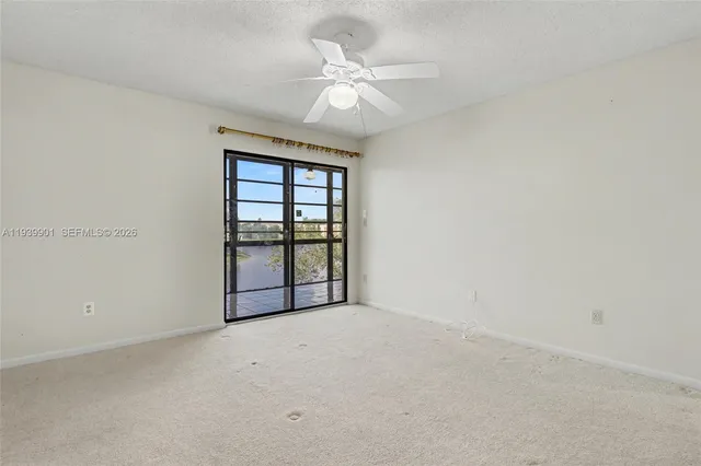 an empty room with chandelier fan and windows