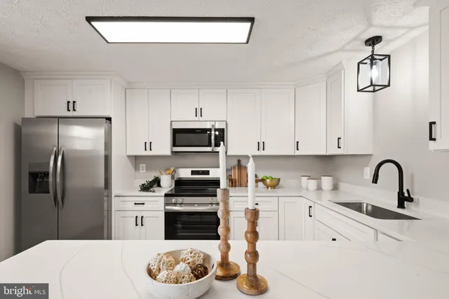 a kitchen with stainless steel appliances granite countertop a sink a stove a refrigerator cabinets and a window