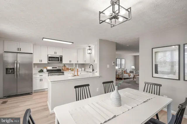 a kitchen with stainless steel appliances a dining table chairs refrigerator and cabinets