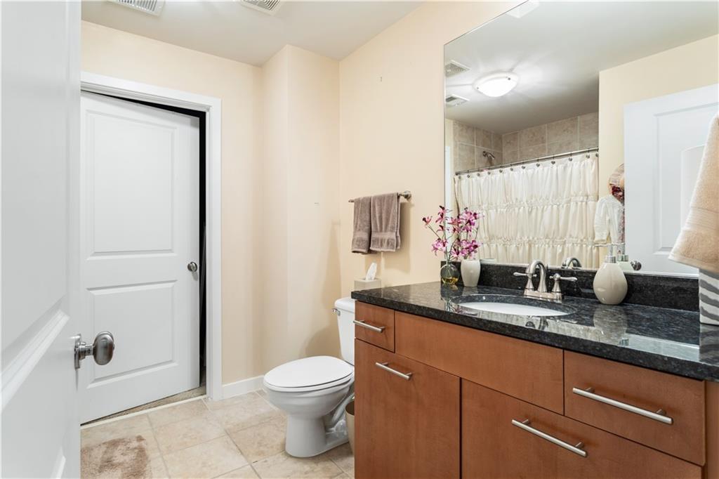 3300 Windy Ridge Parkway Southeast, Unit 713 Atlanta, GA 30339 - Photo 15 of 35 a bathroom with a granite countertop sink a toilet and a mirror