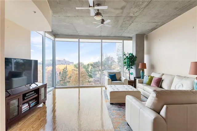 a living room with furniture a flat screen tv and a floor to ceiling window