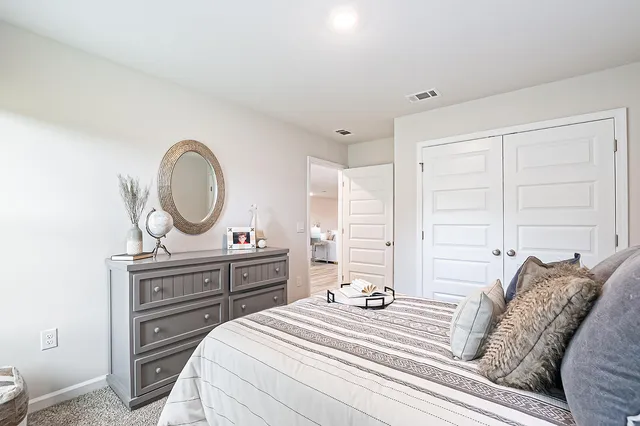 a bedroom with a bed a mirror on dresser and a chandelier