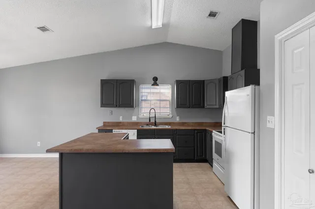a kitchen with a sink refrigerator and cabinets