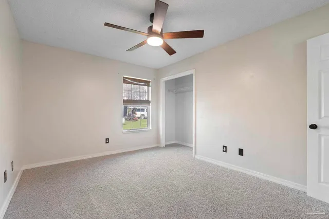 an empty room with a ceiling fan and window