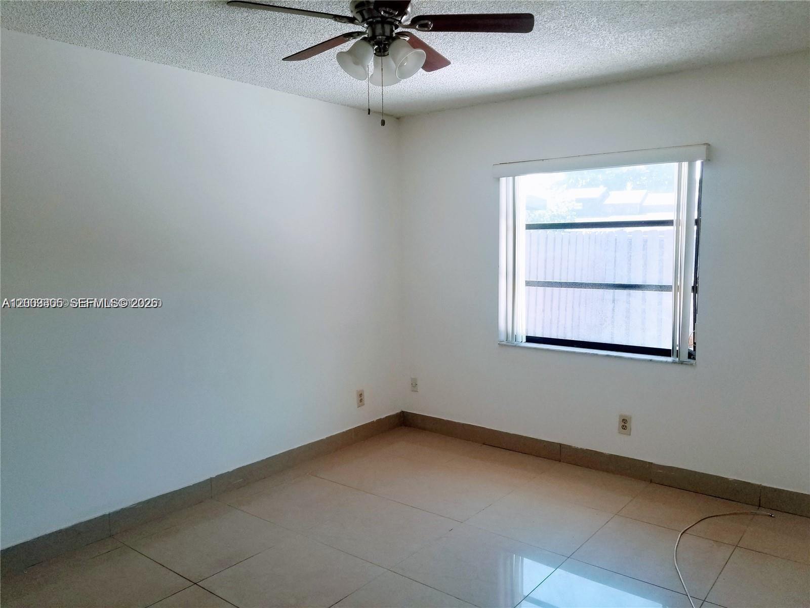 6943 Southwest 40th Street, Unit 11R Miramar, FL 33023 - Photo 6 of 11 an empty room with a window and ceiling fan