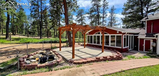11785 Milam Road Colorado Springs, CO 80908 - Photo 27 of 44 View of patio / terrace with a pergola, a sunroom, and a fire pit
