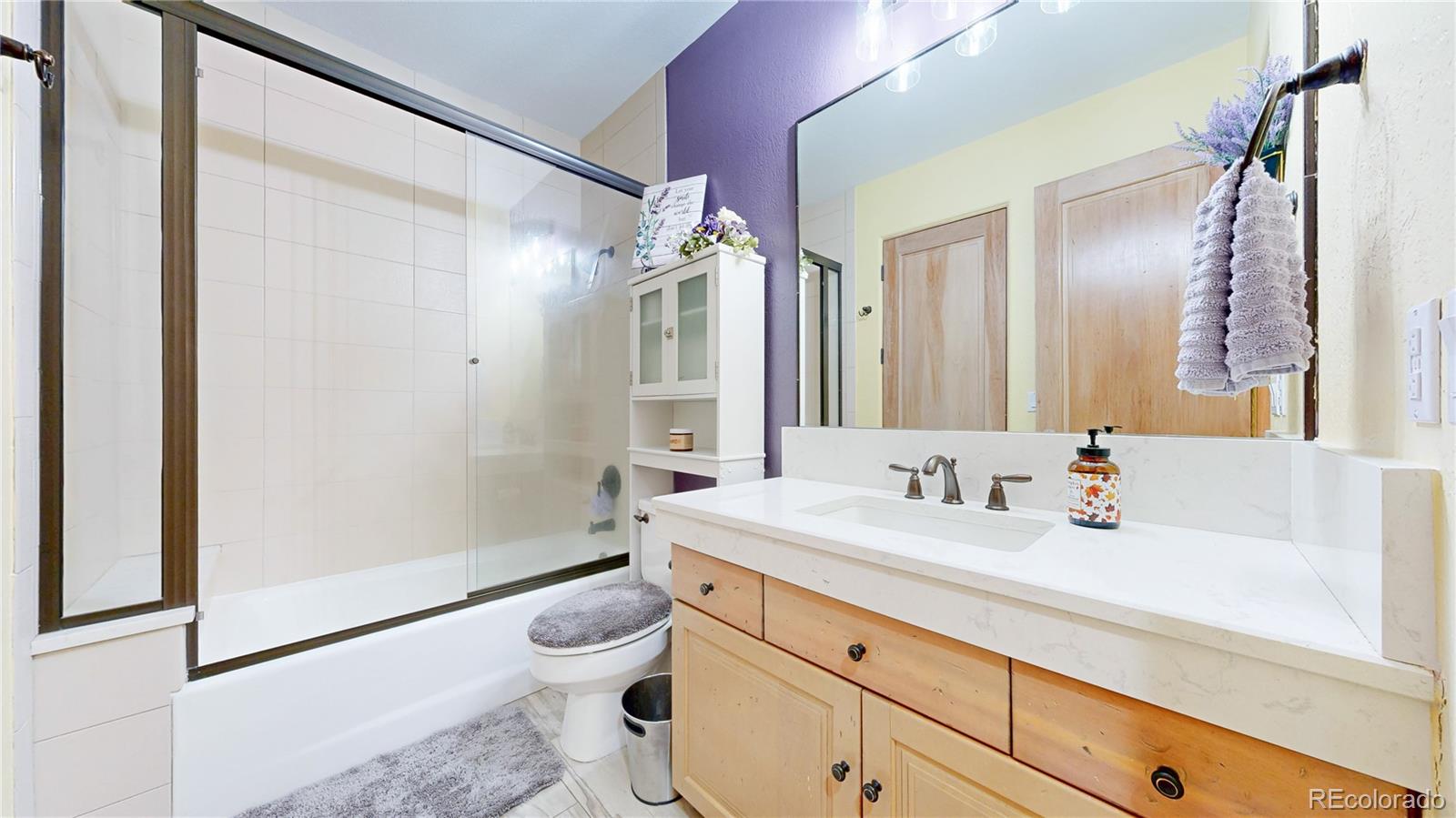 974 Spring Ranch Drive Golden, CO 80401 - Photo 30 of 50 a bathroom with a granite countertop sink a toilet a mirror and shower