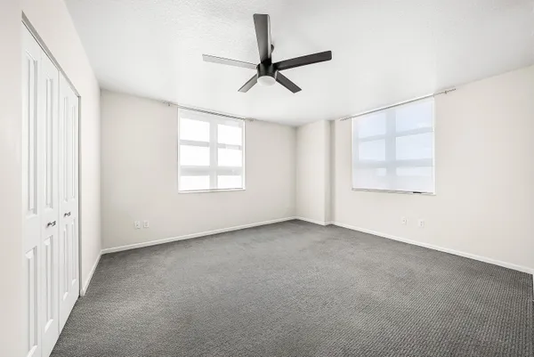 an empty room with windows and fan