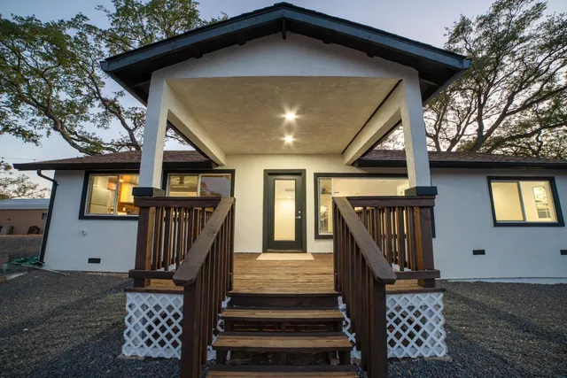 a front view of a house with wooden stairs and furniture