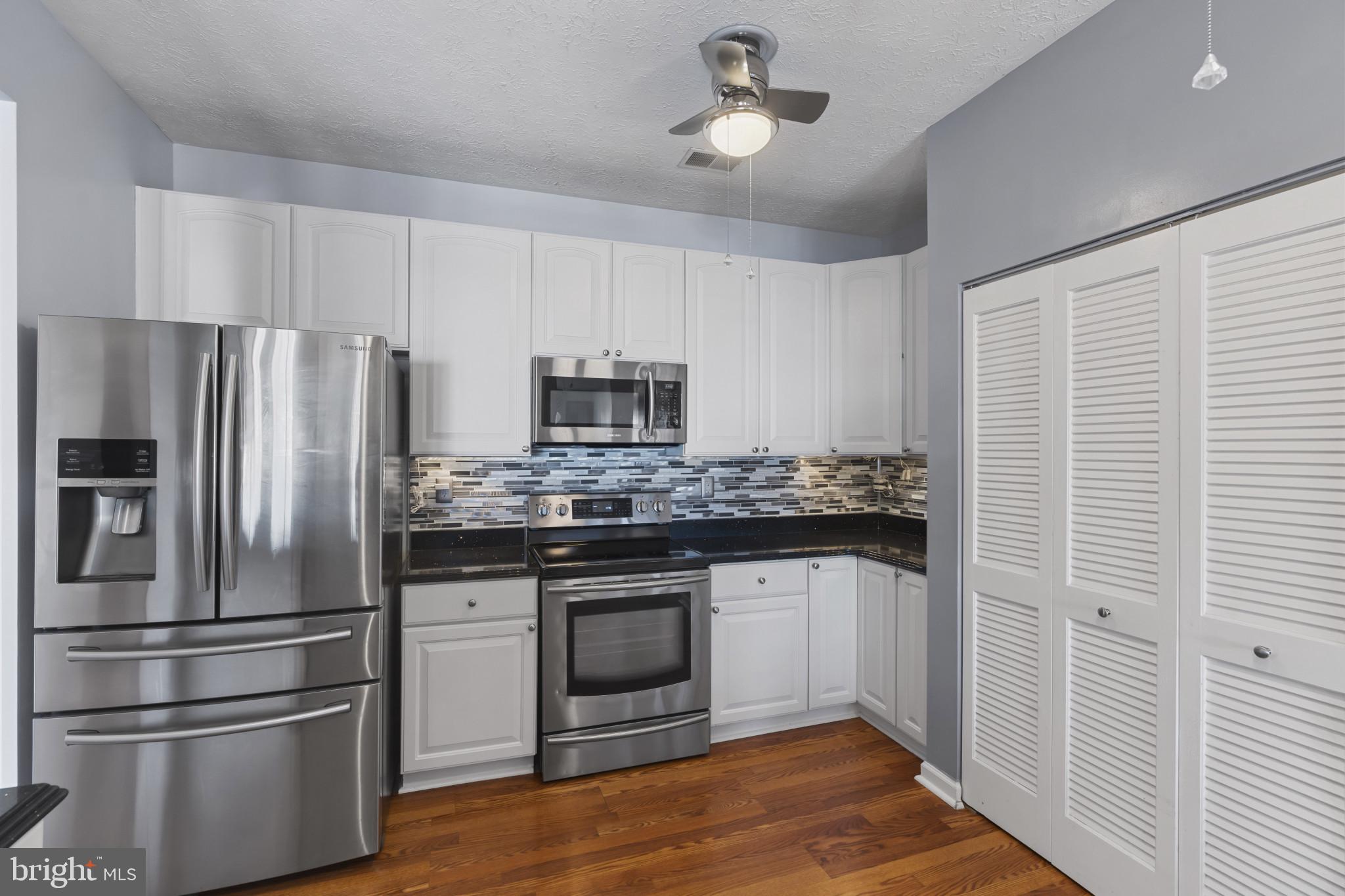 4868 Brightleaf Court, Unit 4868 Rosedale, MD 21237 - Photo 9 of 25 a kitchen with stainless steel appliances wooden floor sink and wooden cabinets