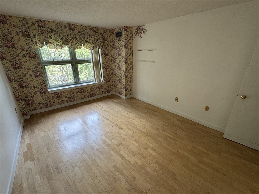 273 Cambridge Road, Unit 202 Woburn, MA 01801 - Photo 29 of 38 an empty room with wooden floor and windows