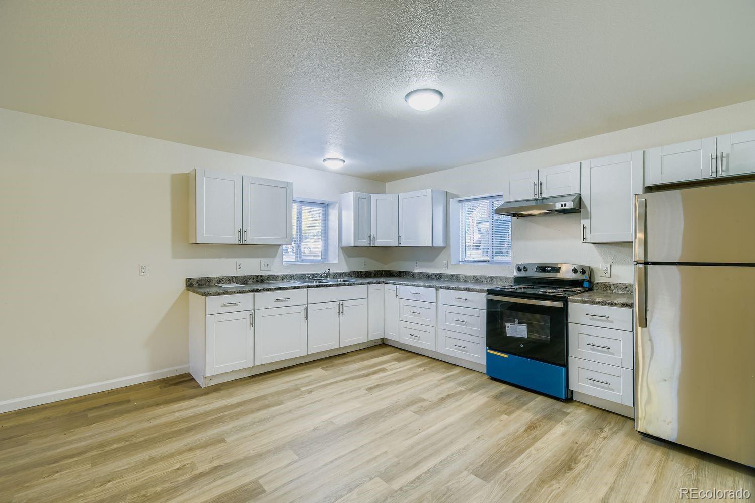 4337 Cook Street Denver, CO 80216 - Photo 3 of 32 a kitchen with granite countertop a refrigerator stove top oven and sink