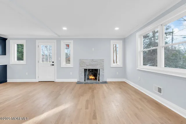 a view of kitchen and empty room with wooden floor and windows
