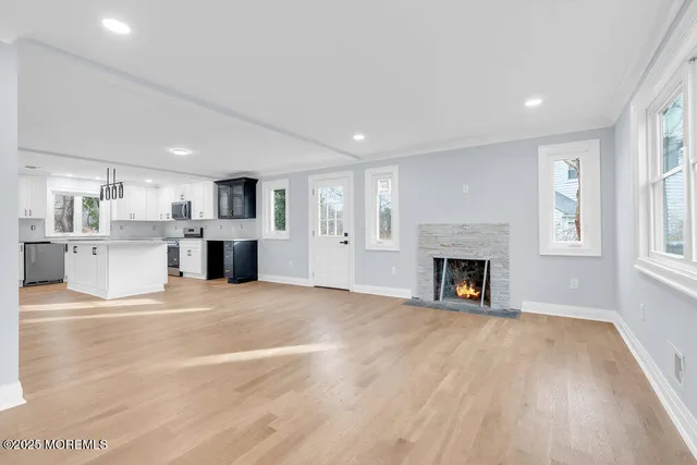 a view of kitchen with stainless steel appliances kitchen island a sink dishwasher a refrigerator and white cabinets with wooden floor