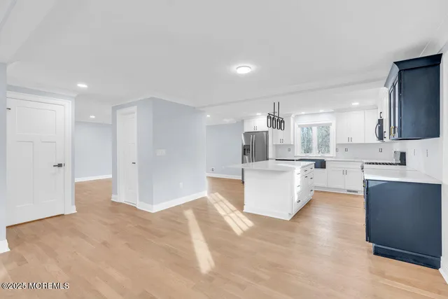 a kitchen with stainless steel appliances granite countertop a sink a stove a refrigerator and white cabinets