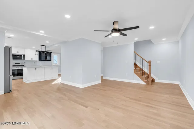 a view of a hallway with wooden floor and a bathroom