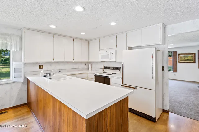 a kitchen with a sink a stove top oven and white stainless steel appliances