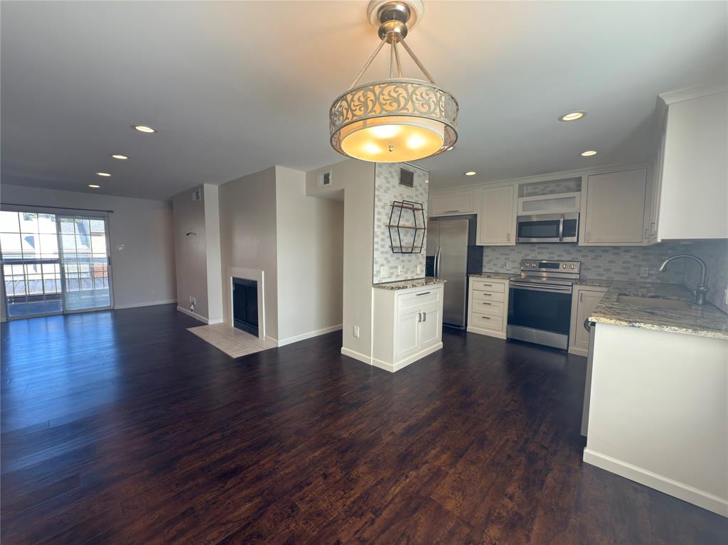 a kitchen with stainless steel appliances granite countertop a refrigerator a stove oven a sink dishwasher and white cabinets with wooden floor