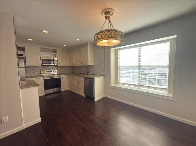 a kitchen with stainless steel appliances granite countertop a stove a refrigerator and a wooden floor