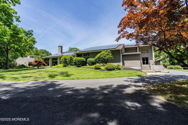 a view of a house with a big yard and large trees