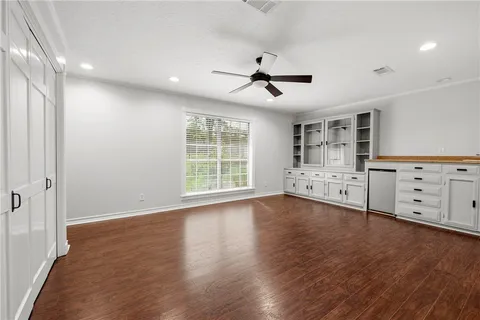 a view of an empty room with a window and wooden floor