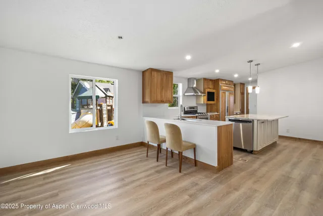 a kitchen with kitchen island granite countertop wooden floors and white stainless steel appliances