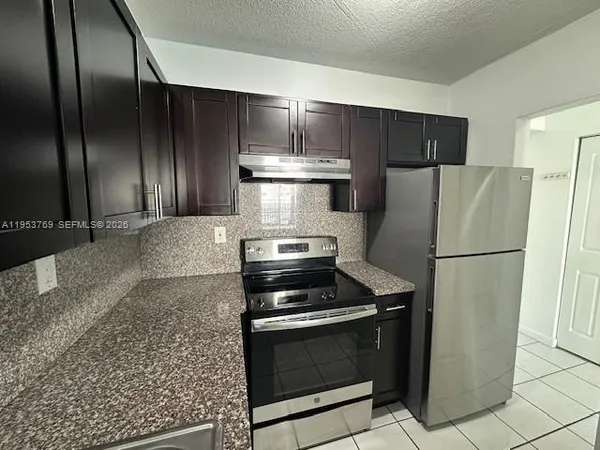 a metallic refrigerator freezer and a stove sitting inside of a kitchen