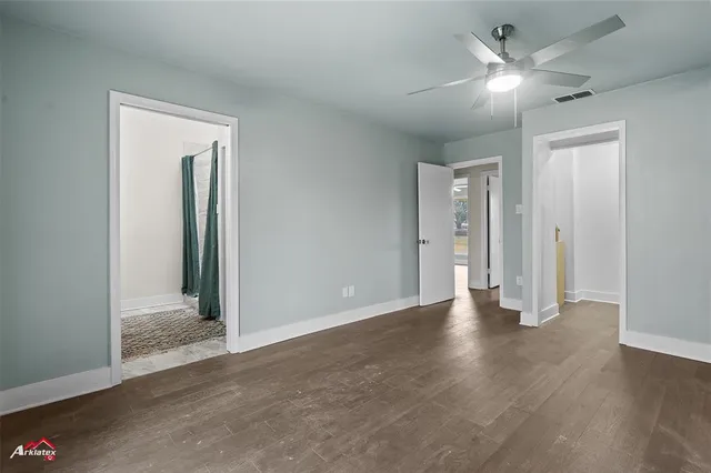 an empty room with wooden floor and ceiling fan