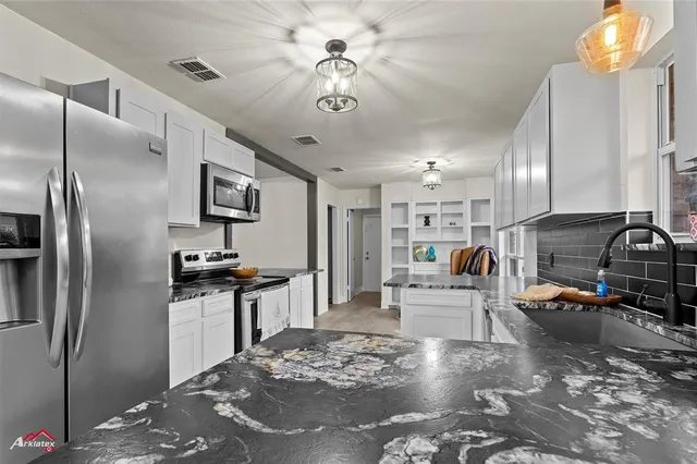 a kitchen with stainless steel appliances kitchen island granite countertop a refrigerator a stove a sink a dining table and chairs with wooden floor