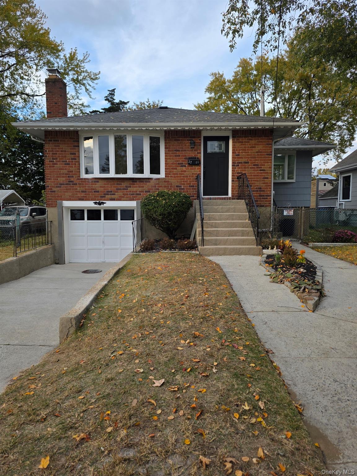 View of front of home with brick siding, a chimney, concrete driveway, and a garage