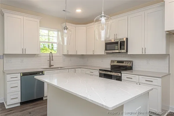 a kitchen with stainless steel appliances a stove a sink a microwave and cabinets