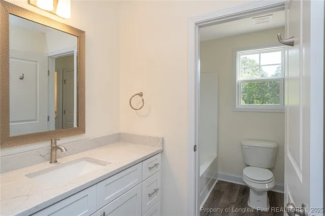 a bathroom with a granite countertop sink a toilet and a mirror