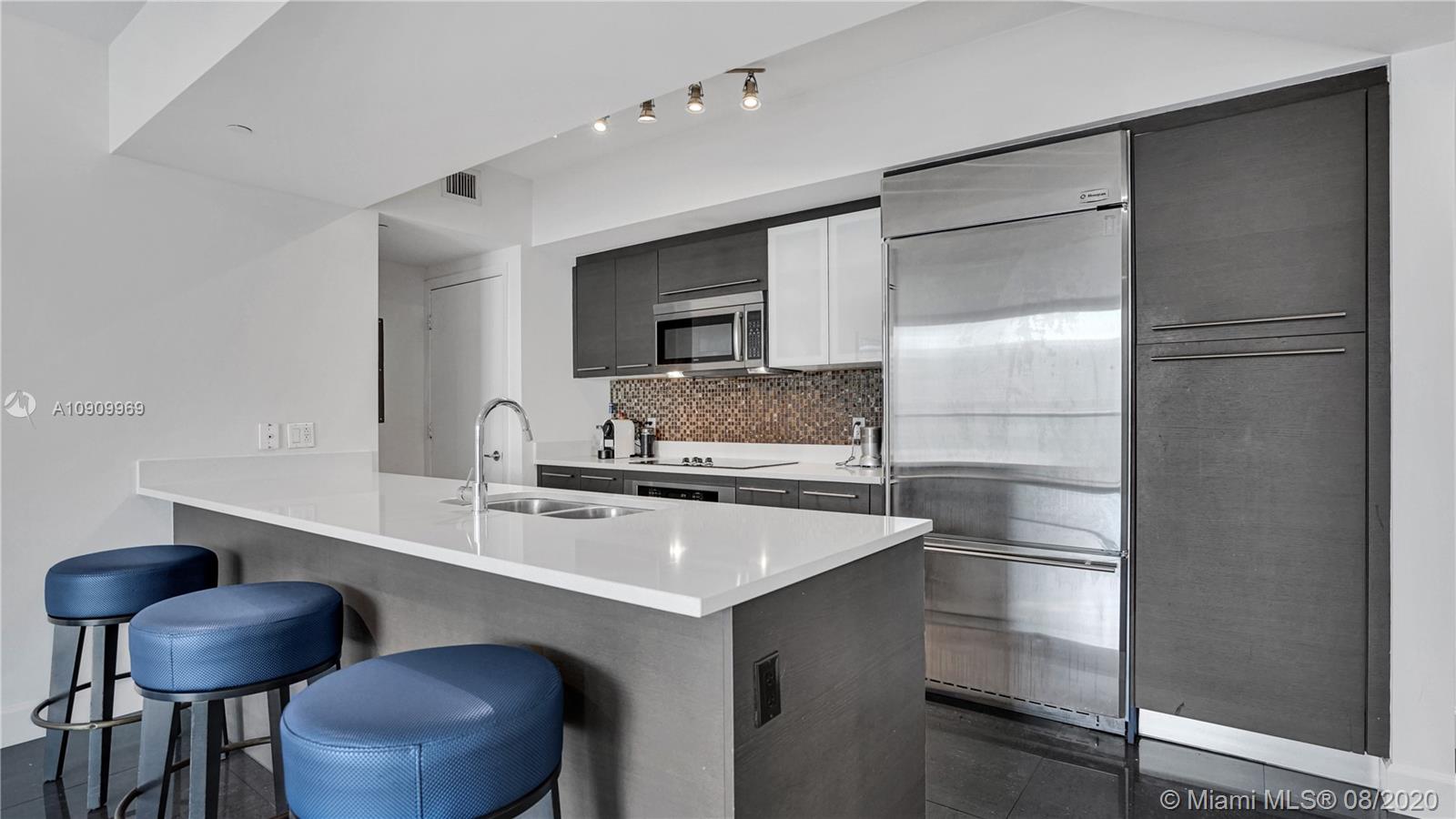 55 Southeast 6th Street, Unit 1903 Miami, FL 33131 - Photo 2 of 26 a kitchen with a sink cabinets and chairs