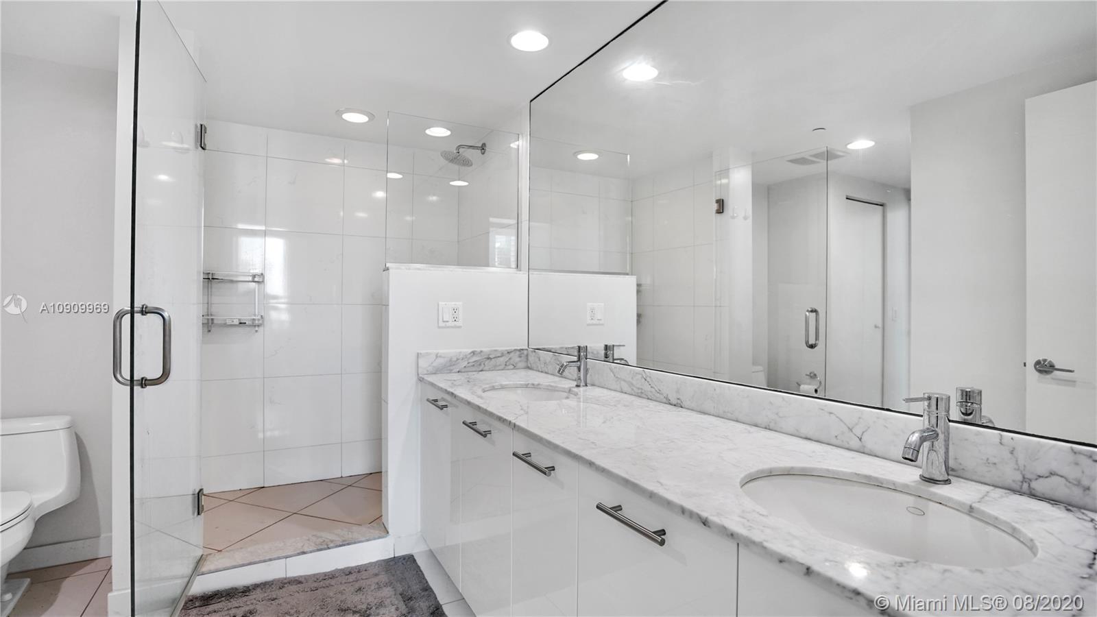 55 Southeast 6th Street, Unit 1903 Miami, FL 33131 - Photo 15 of 26 a bathroom with a granite countertop sink mirror and shower