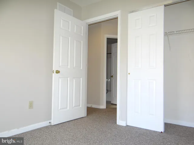a view of an empty room with closet and a bathroom