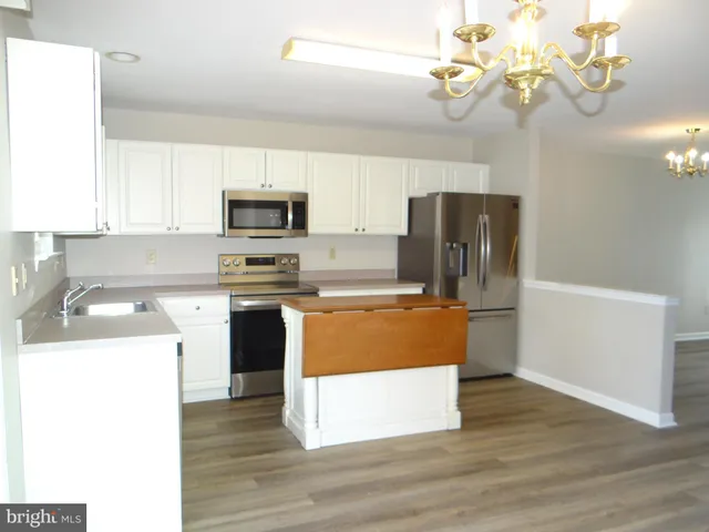 a kitchen with stainless steel appliances granite countertop a refrigerator a stove top oven a sink and dishwasher with wooden floor