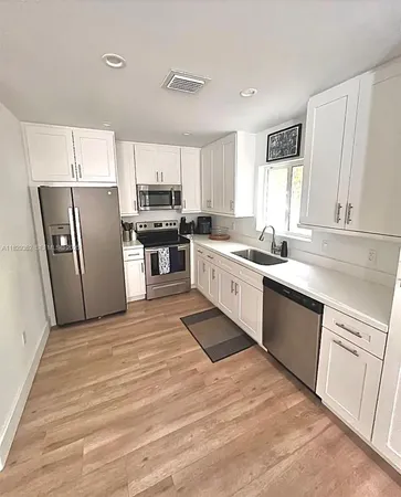 a kitchen with stainless steel appliances granite countertop a sink stove refrigerator and cabinets