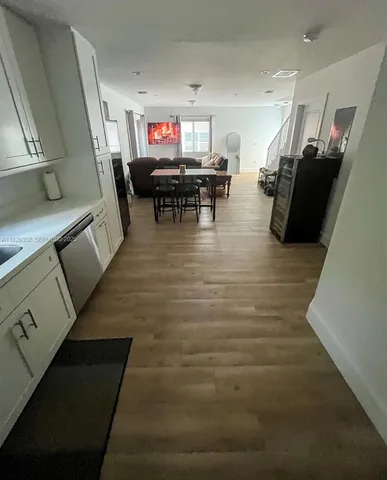 a living room with furniture and a dining table with wooden floor